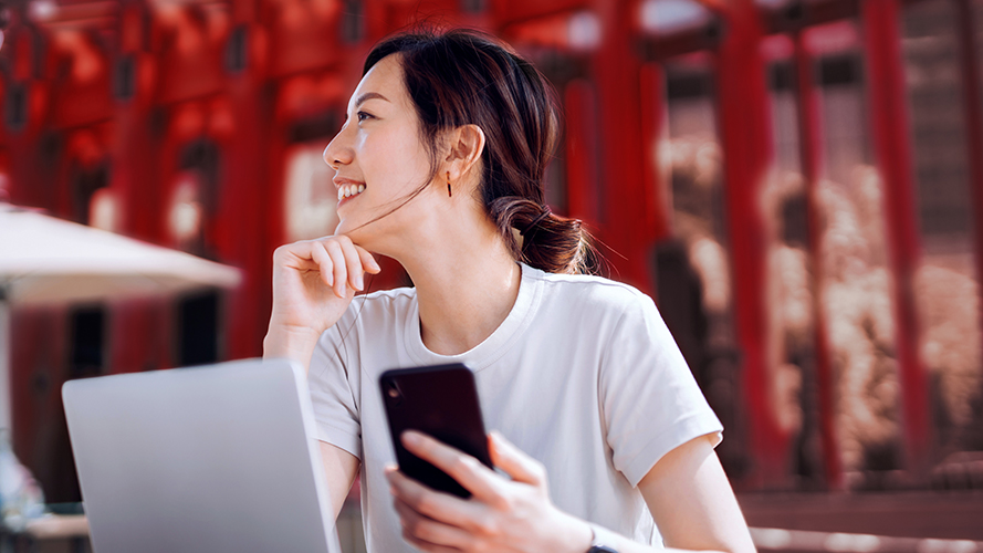 Smiling woman holding the phone, preparing to study abroad, with her HSBC Premier accountke the first step in studying abroad